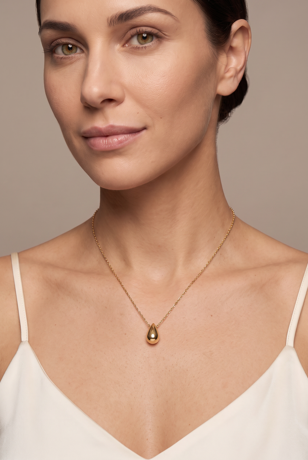 Gold teardrop pendant necklace worn at the collarbone