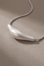 Close-up of the brushed bar pendant threaded on the snake chain