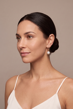 Rose-gold-tone pearl drop earring worn on the ear