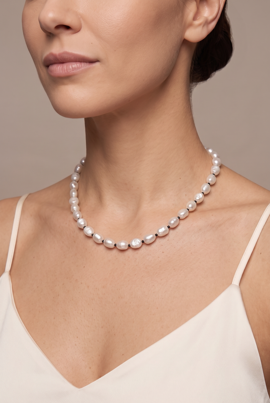 White baroque pearl necklace with black spacers worn at the collarbone